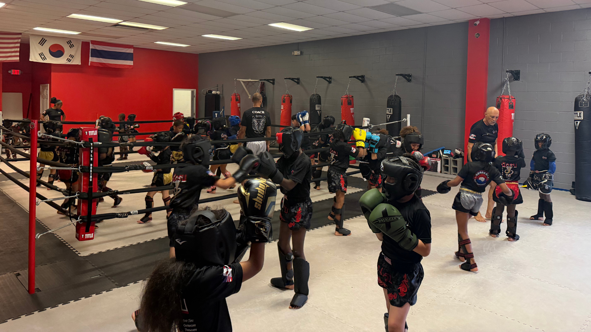 Kids in protective gear sparring on the mats at our martial arts academy